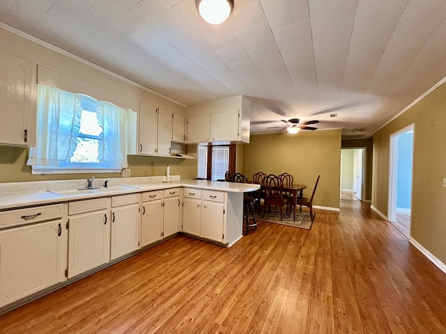 kitchen featuring white cabinetry, sink, light hardwood / wood-style floors, and kitchen peninsula