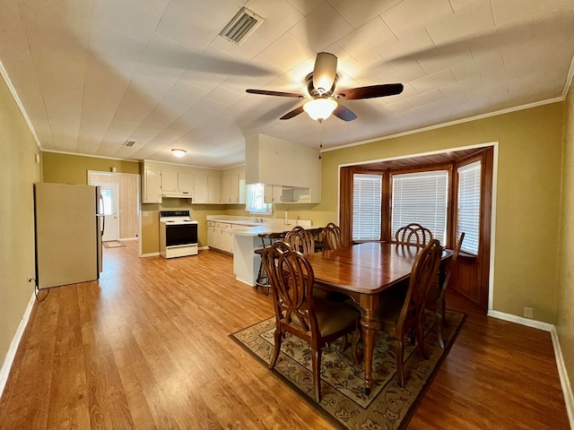 dining area featuring sink, crown molding, ceiling fan, and light wood-type flooring