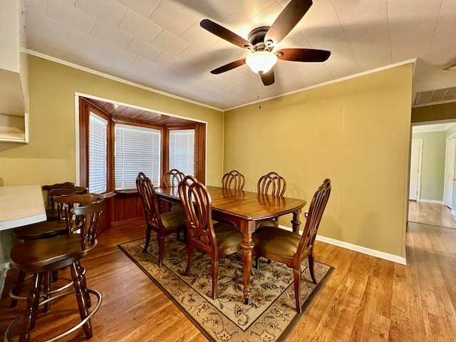 dining space with crown molding, light hardwood / wood-style flooring, and ceiling fan