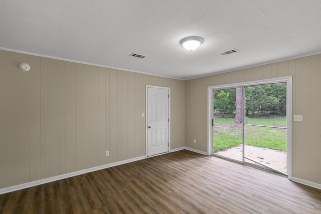 unfurnished room featuring baseboards, visible vents, a textured ceiling, and wood finished floors