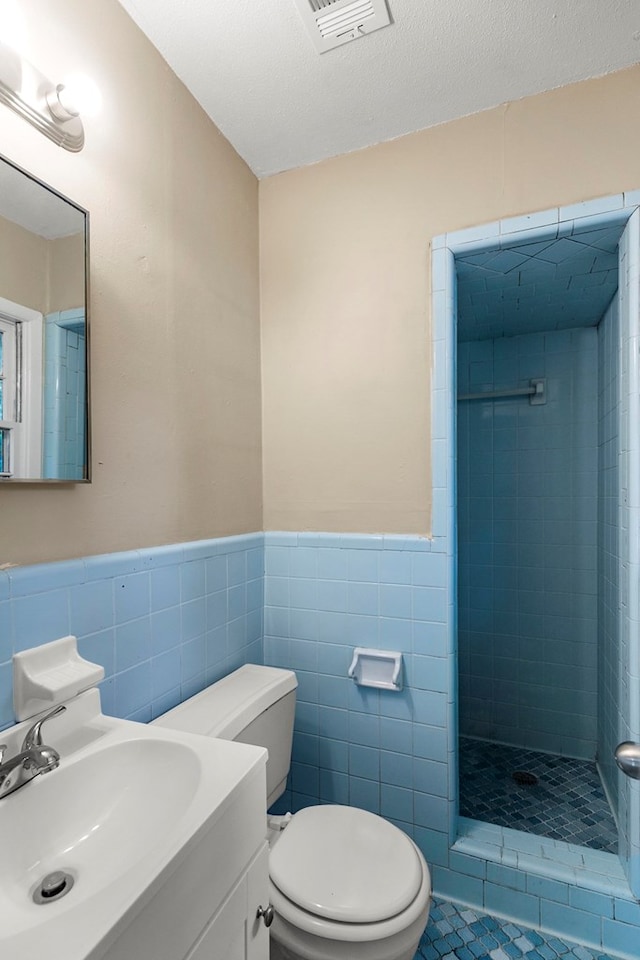 full bath with a wainscoted wall, tile walls, a shower stall, and toilet