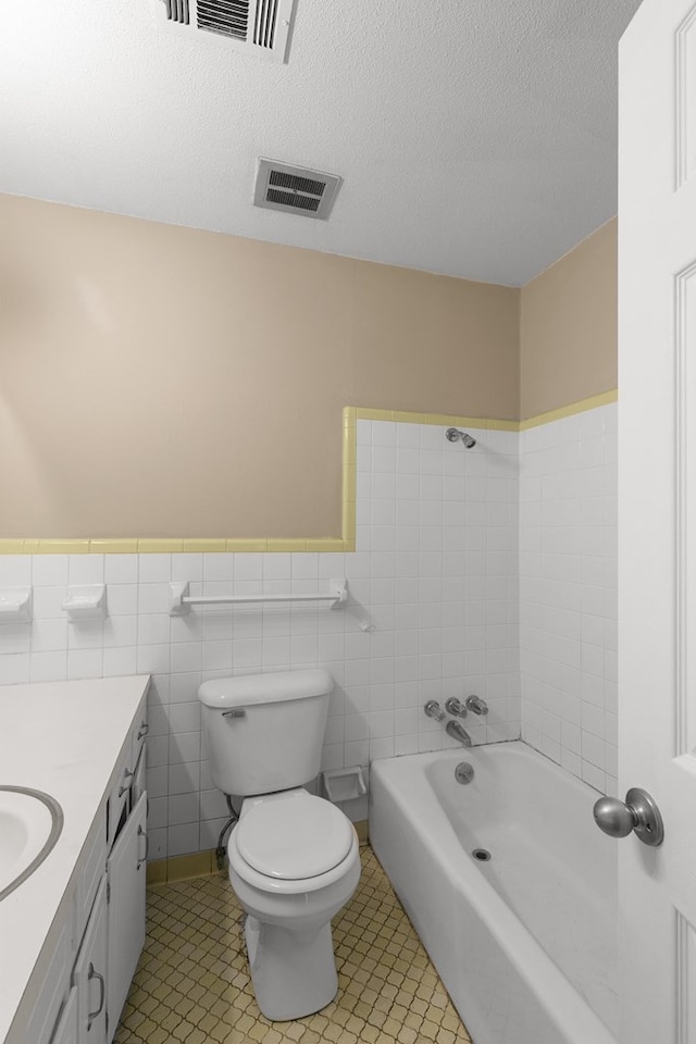 bathroom featuring a bathtub, toilet, wainscoting, visible vents, and vanity