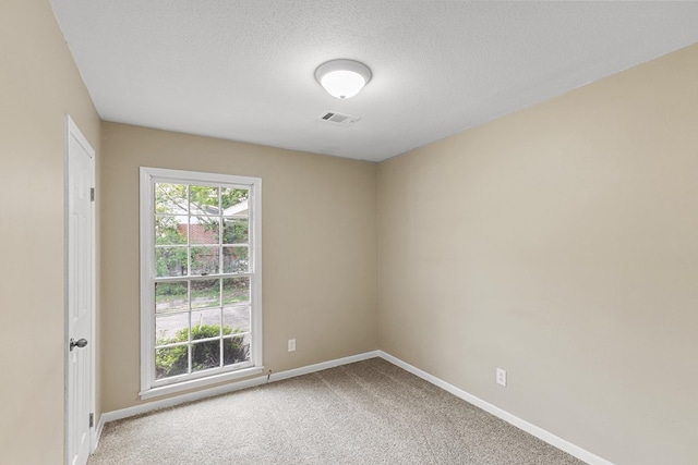 carpeted spare room with a textured ceiling, visible vents, and baseboards