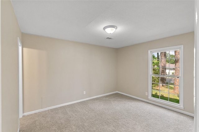 carpeted spare room featuring baseboards and a textured ceiling