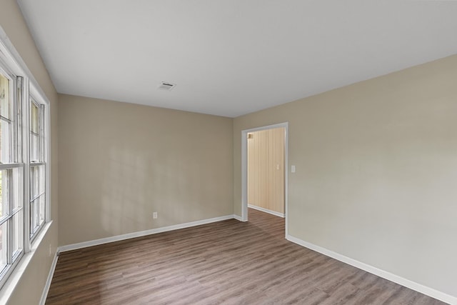 unfurnished room with baseboards, a wealth of natural light, visible vents, and wood finished floors