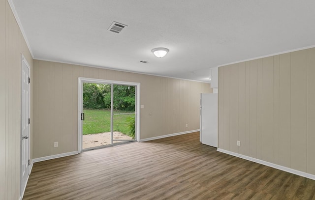 empty room featuring baseboards, visible vents, crown molding, and wood finished floors