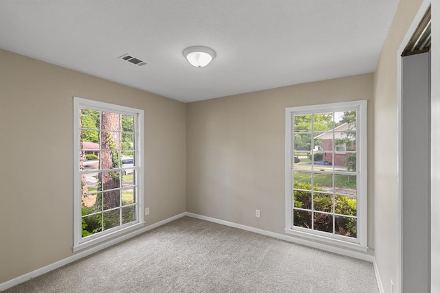 spare room featuring a wealth of natural light, visible vents, and carpet