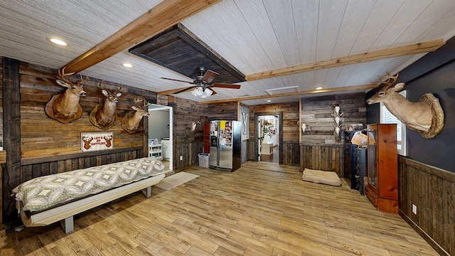 interior space with wood walls, wooden ceiling, light wood-type flooring, stainless steel fridge, and beamed ceiling