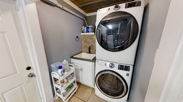 washroom featuring sink, light tile patterned floors, cabinets, and stacked washer / drying machine