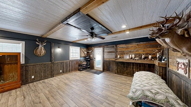 bar featuring ceiling fan, beam ceiling, dark brown cabinets, light hardwood / wood-style floors, and wood walls