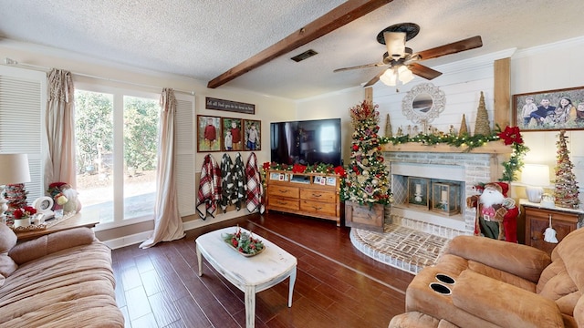 living room featuring ceiling fan, dark hardwood / wood-style floors, a fireplace, ornamental molding, and a textured ceiling