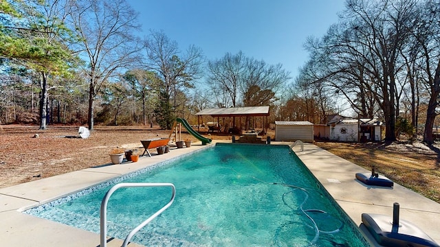 view of swimming pool with a water slide, a patio area, and a storage unit