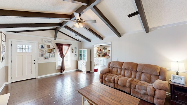 living room featuring ceiling fan, dark wood-type flooring, vaulted ceiling with beams, and a textured ceiling