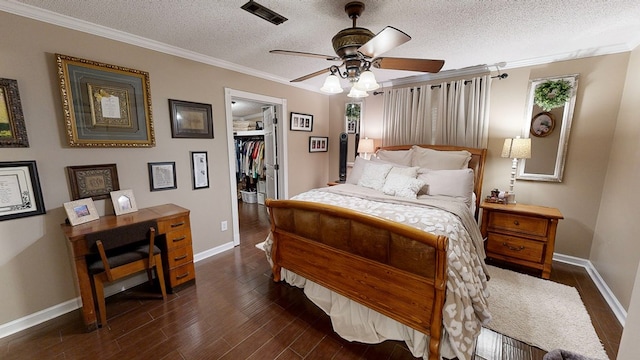 bedroom with dark hardwood / wood-style floors, a spacious closet, ceiling fan, crown molding, and a textured ceiling