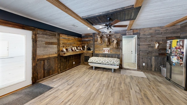 bar with beamed ceiling, wood walls, stainless steel fridge, and light hardwood / wood-style flooring