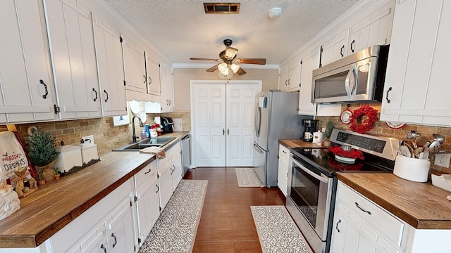 kitchen featuring stainless steel appliances, wooden counters, and white cabinets