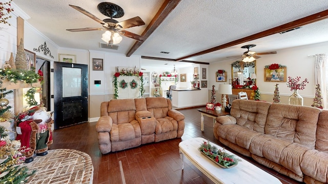 living room featuring beamed ceiling, dark hardwood / wood-style flooring, ornamental molding, ceiling fan, and a textured ceiling