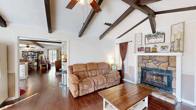 living room featuring dark wood-type flooring, a stone fireplace, lofted ceiling with beams, and a textured ceiling