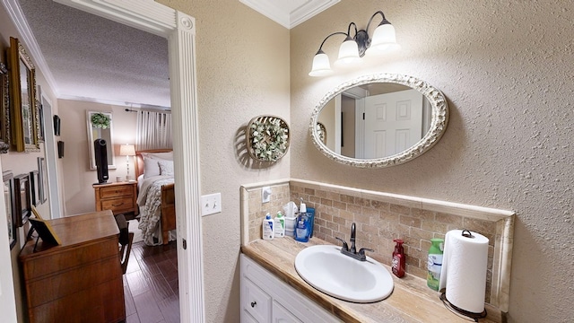 bathroom featuring vanity, hardwood / wood-style flooring, ornamental molding, and a textured ceiling