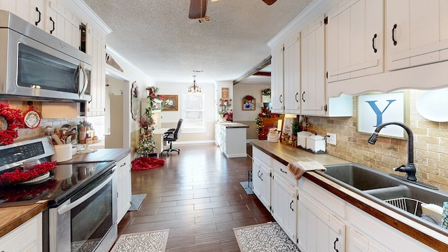 kitchen featuring appliances with stainless steel finishes, white cabinets, and wood counters