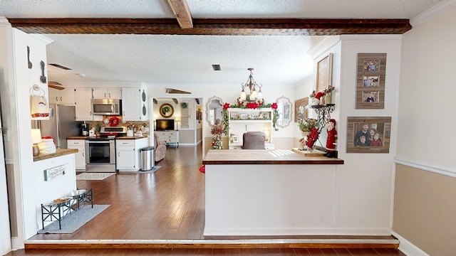 kitchen featuring pendant lighting, white cabinets, stainless steel appliances, dark wood-type flooring, and a textured ceiling