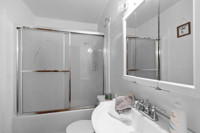 full bathroom with combined bath / shower with glass door, toilet, sink, and a textured ceiling