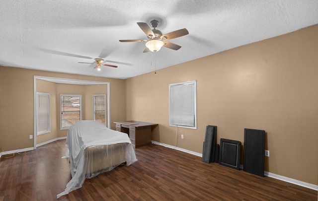 bedroom with ceiling fan, dark wood-type flooring, and a textured ceiling