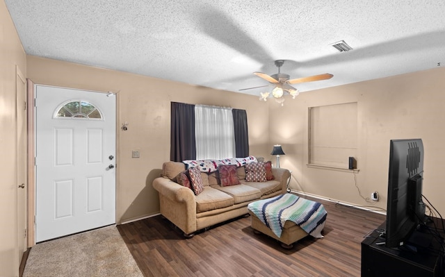 living room with ceiling fan, dark wood-type flooring, and a textured ceiling