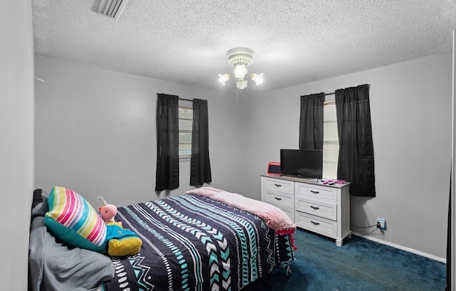 bedroom featuring multiple windows, dark carpet, and a textured ceiling