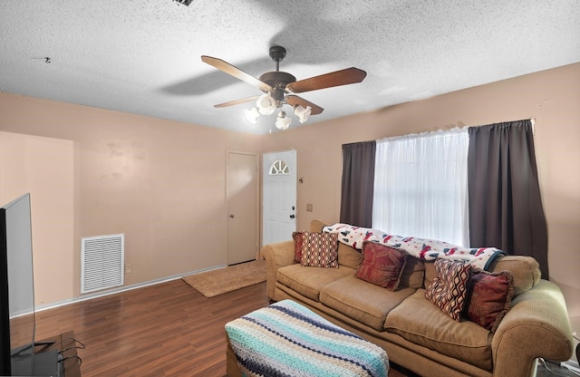 living room featuring ceiling fan, dark hardwood / wood-style flooring, and a textured ceiling