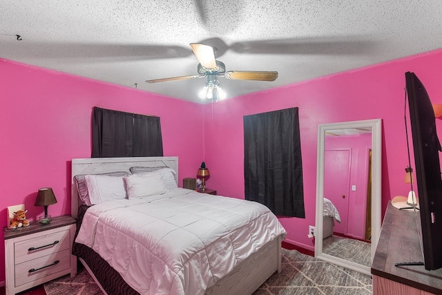 bedroom with a textured ceiling, dark carpet, and ceiling fan