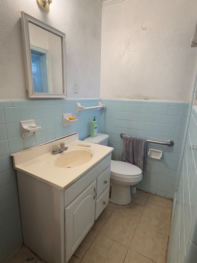 bathroom featuring toilet, vanity, tile walls, and tile patterned floors