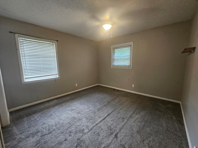 carpeted empty room with baseboards, a ceiling fan, and a textured ceiling