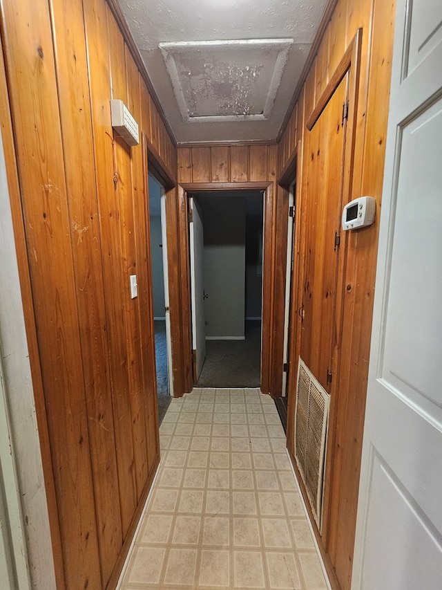 hall with visible vents, wood walls, and light floors