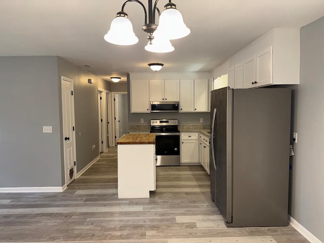 471 Faith St, Enterprise, AL 36330 - kitchen featuring stainless steel appliances, white cabinetry, light wood-type flooring, a chandelier, and decorative light fixtures