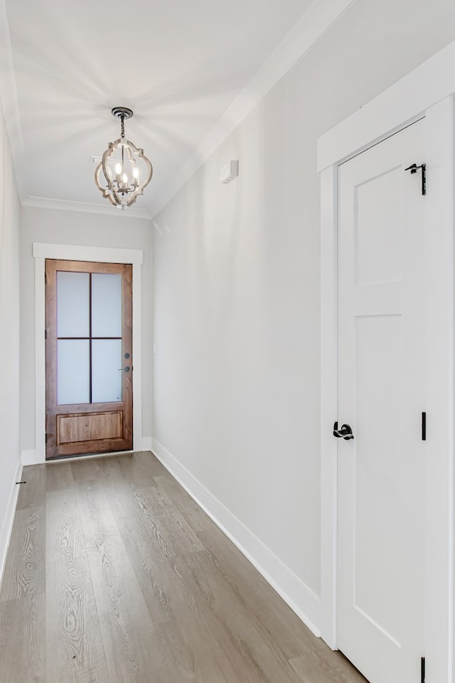 empty room featuring an inviting chandelier, ornamental molding, and light wood-type flooring