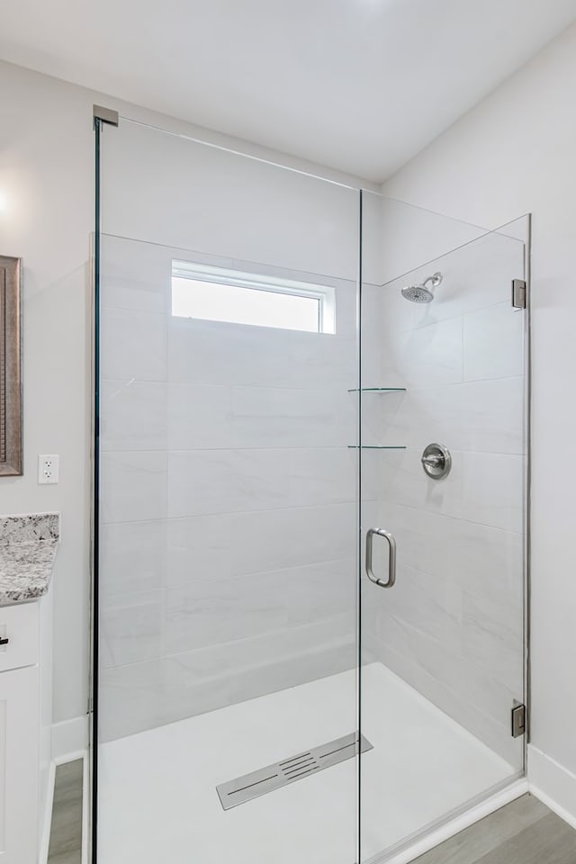 bathroom with hardwood / wood-style flooring, vanity, and an enclosed shower