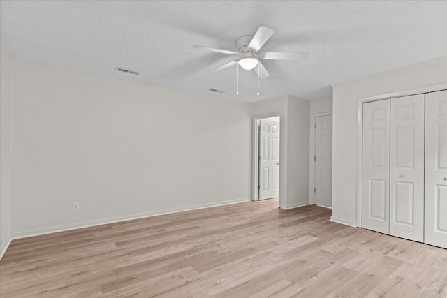 unfurnished bedroom featuring light wood-style flooring, a textured ceiling, baseboards, a closet, and a ceiling fan