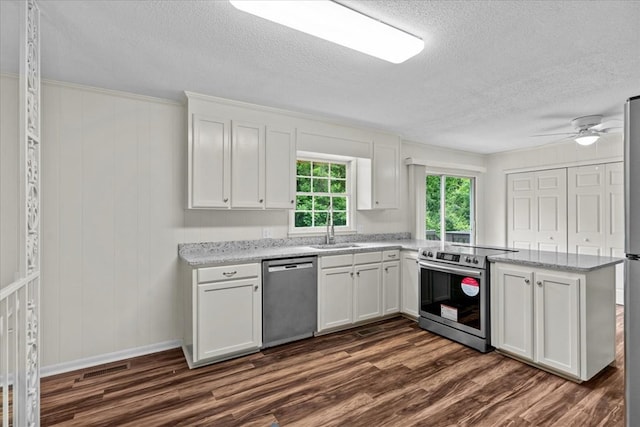 kitchen with stainless steel appliances, dark wood-style flooring, a textured ceiling, a peninsula, and white cabinets
