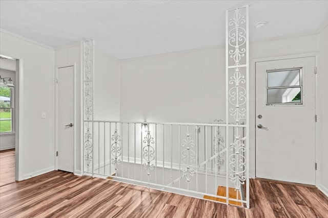 empty room with wood finished floors, crown molding, a smoke detector, and baseboards