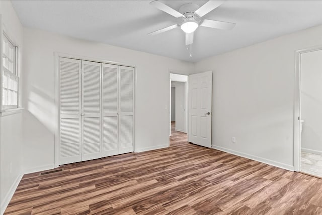 unfurnished bedroom featuring wood finished floors, a closet, and baseboards