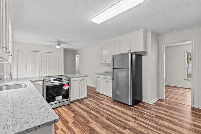 kitchen with stainless steel appliances, ceiling fan, white cabinets, wood finished floors, and a textured ceiling