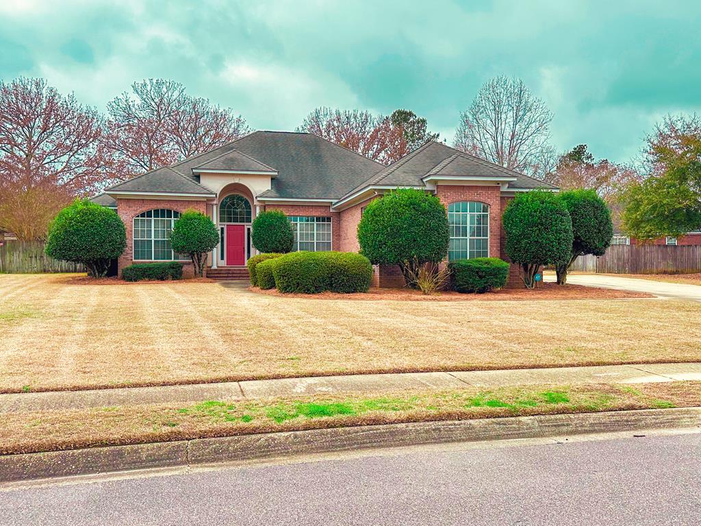 view of front facade featuring brick siding, a front yard, and fence