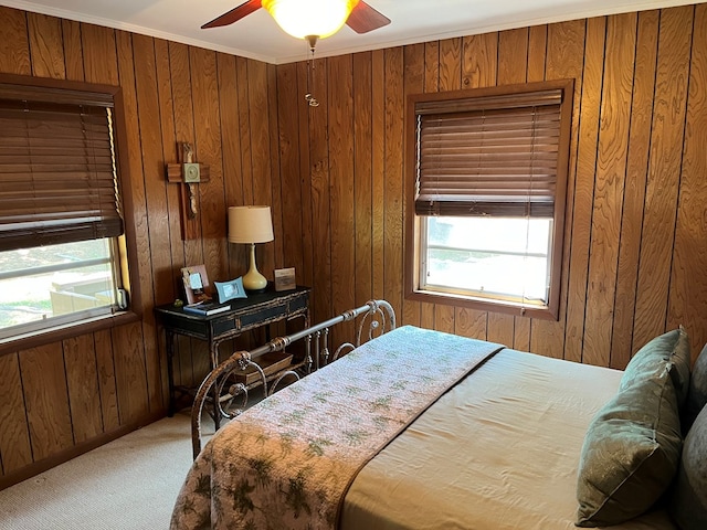 carpeted bedroom featuring crown molding, ceiling fan, and wooden walls