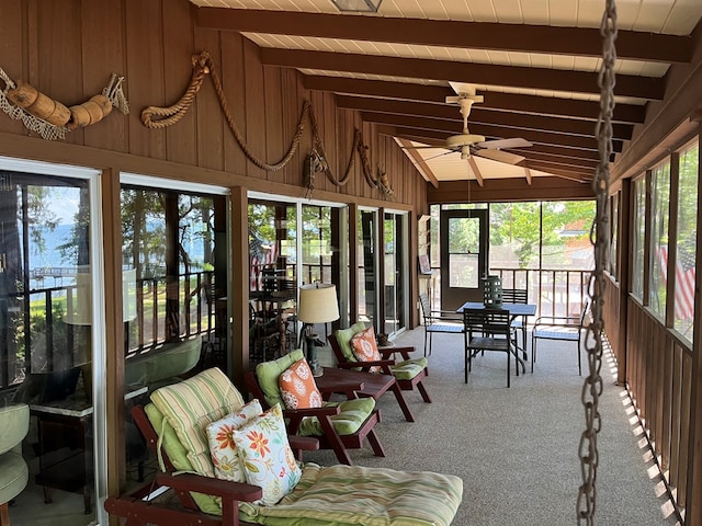 sunroom with ceiling fan, a wealth of natural light, lofted ceiling with beams, and wooden ceiling