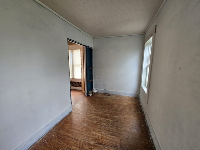 empty room with dark wood-type flooring and ornamental molding