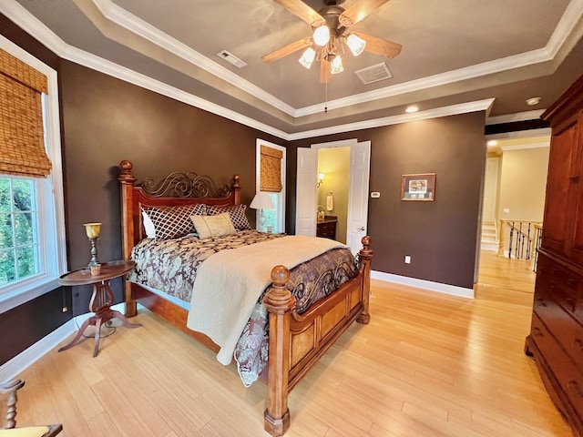 bedroom featuring a tray ceiling, light hardwood / wood-style flooring, ceiling fan, and crown molding