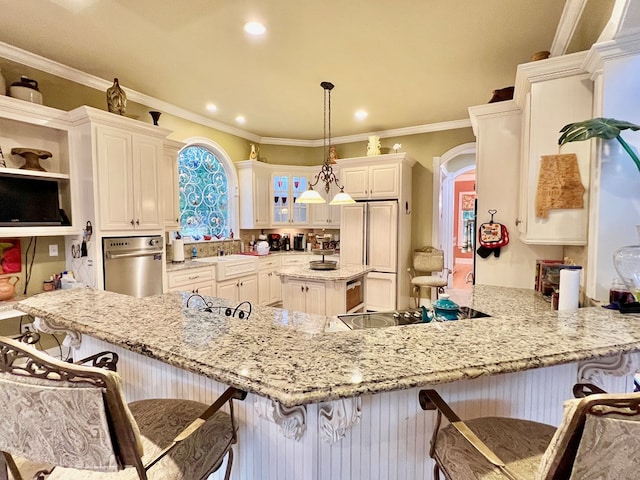 kitchen featuring kitchen peninsula, a kitchen bar, light stone counters, ornamental molding, and hanging light fixtures