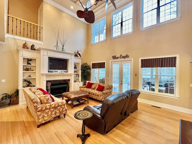 living room featuring ceiling fan, light wood-type flooring, and a high ceiling