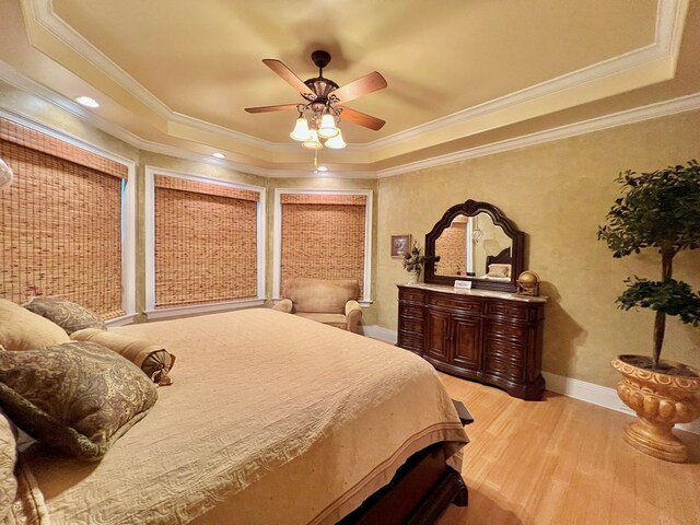 bedroom with a tray ceiling, light hardwood / wood-style flooring, ceiling fan, and ornamental molding